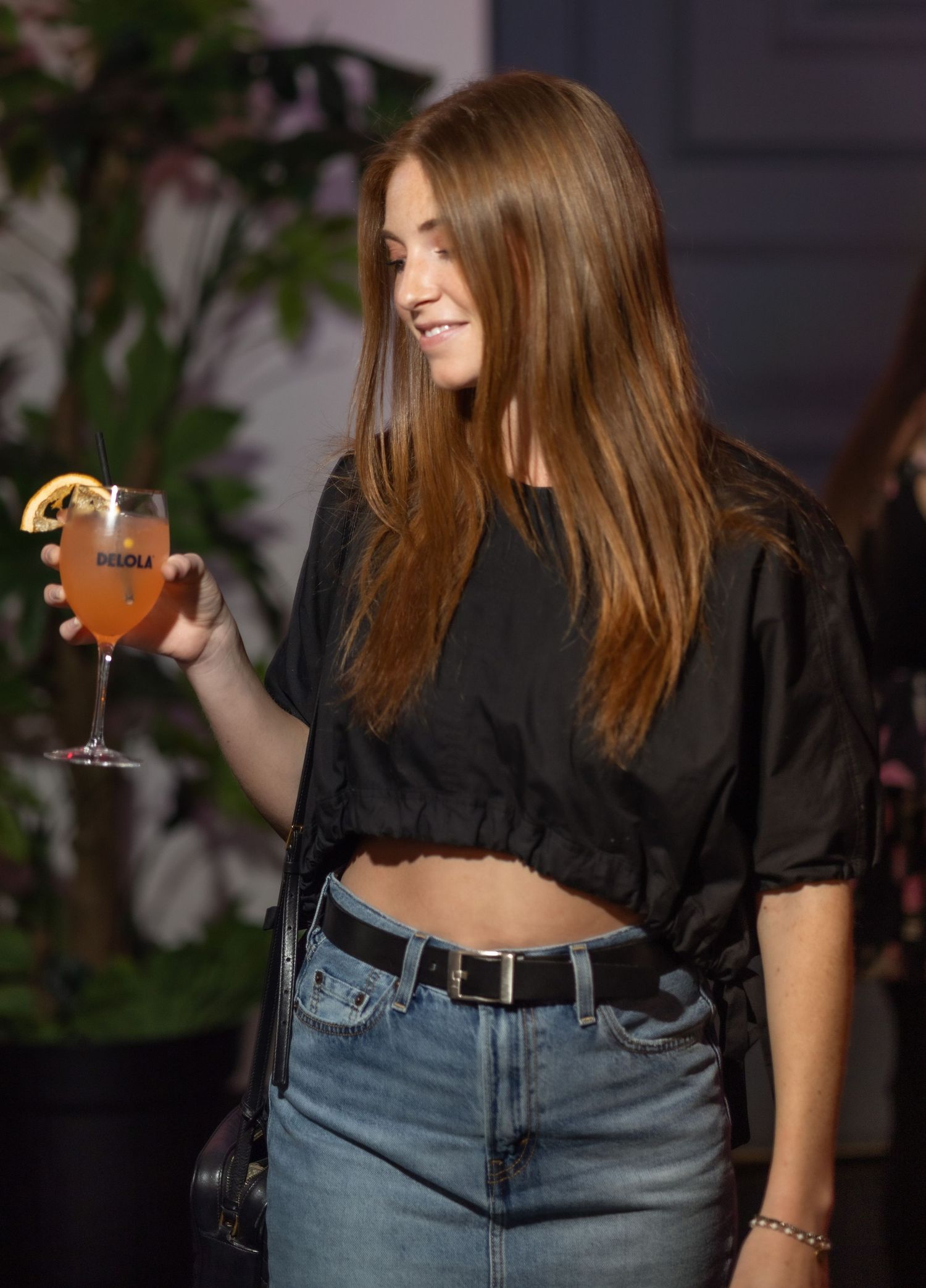 Guest holding orange cocktail at evening social event.