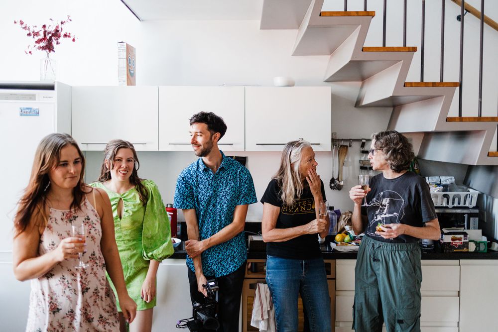 A casual group of friends chatting and laughing together in a modern kitchen setting.