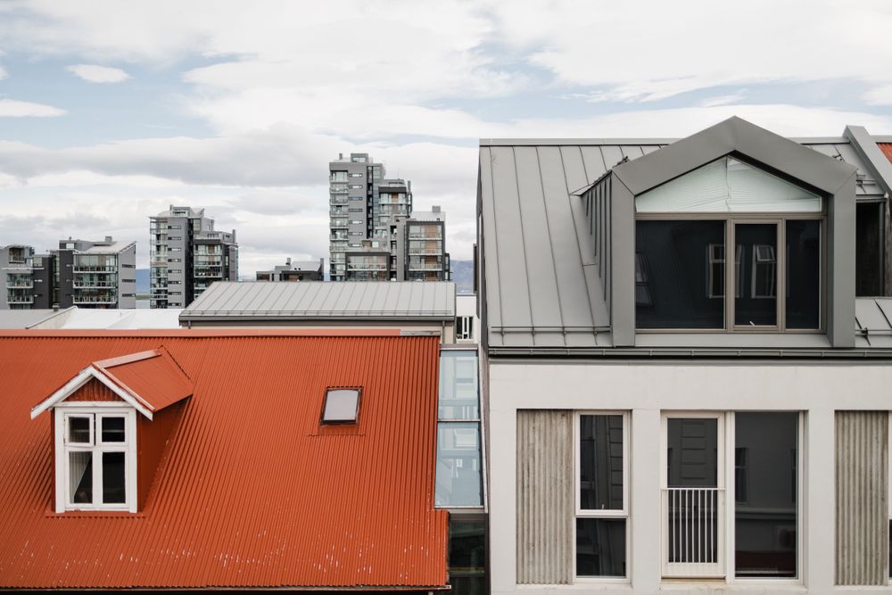 Modern urban architecture with orange and grey buildings against a cloudy sky.