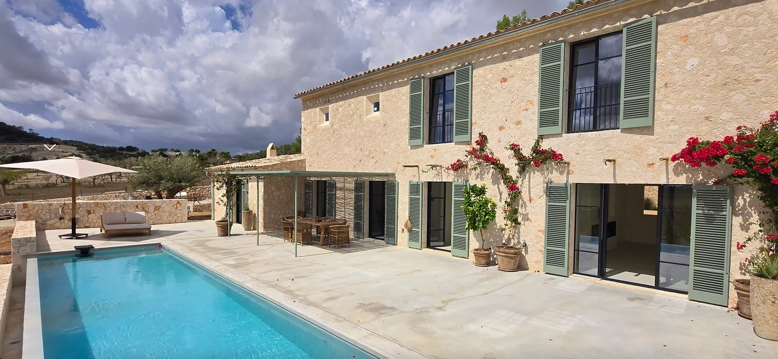A luxury Mediterranean villa with panoramic views features a long infinity pool overlooking the countryside landscape.