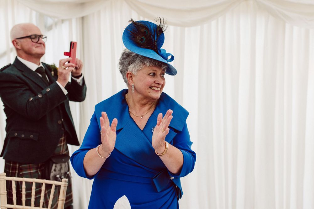 Wedding guests in formal attire dance and celebrate at an indoor reception venue.
