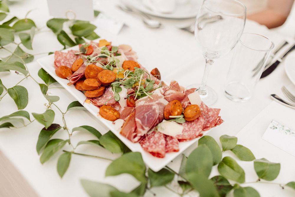 Charcuterie and appetizer platters garnished with fresh herbs at a wedding reception.