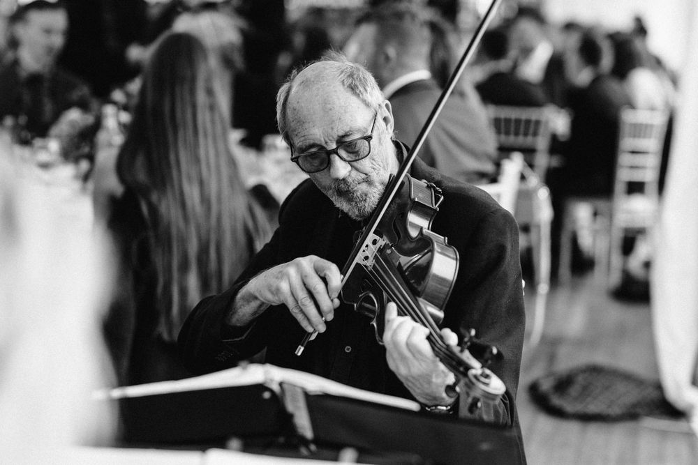 Musicians performing with violins at an elegant wedding reception in black and white.