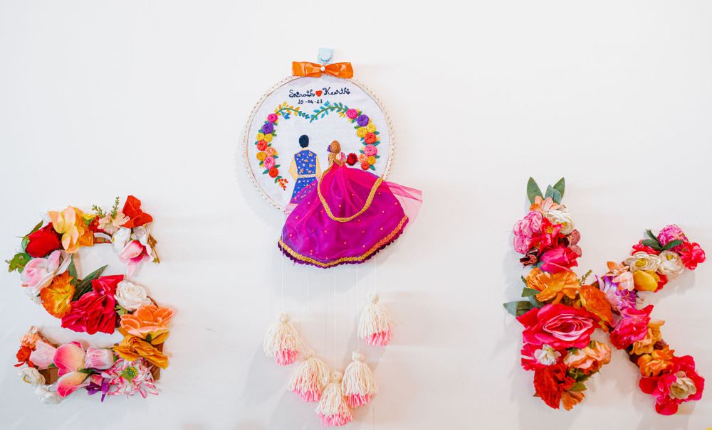 Wedding decor featuring embroidery hoops and pink tassels against white background.