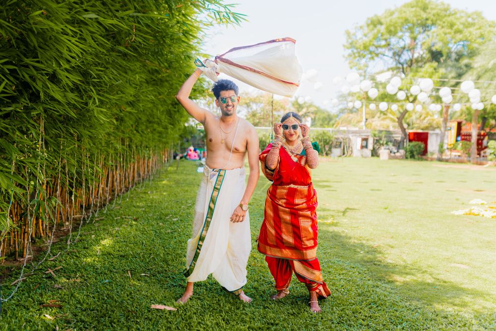 Couple in traditional attire dancing joyfully in garden setting.