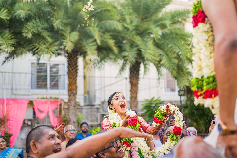 Celebratory moment at Indian wedding with flower petals being tossed amid palm trees.