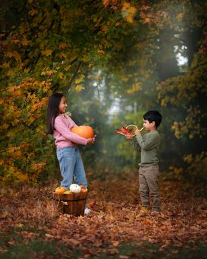 Children playing together in autumn leaves under orange and yellow foliage on a misty fall day.
