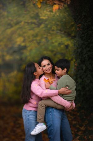 A loving family moment captured in autumn with warm embraces against a backdrop of fall foliage.