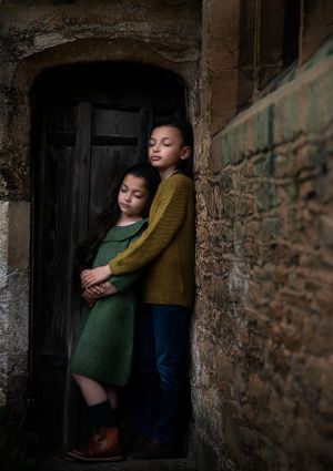 brother and sister hugging each other whilst leaning on an ancient church door