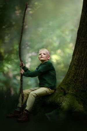 young boy sat with a staff on the stump of a mossy tree looking into the future like a wizard or in his words a jedi