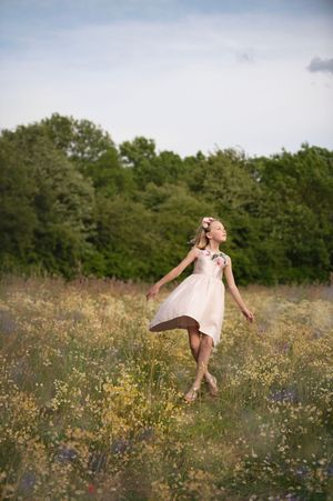Figure twirling joyfully in a sundress among wildflowers at golden hour.