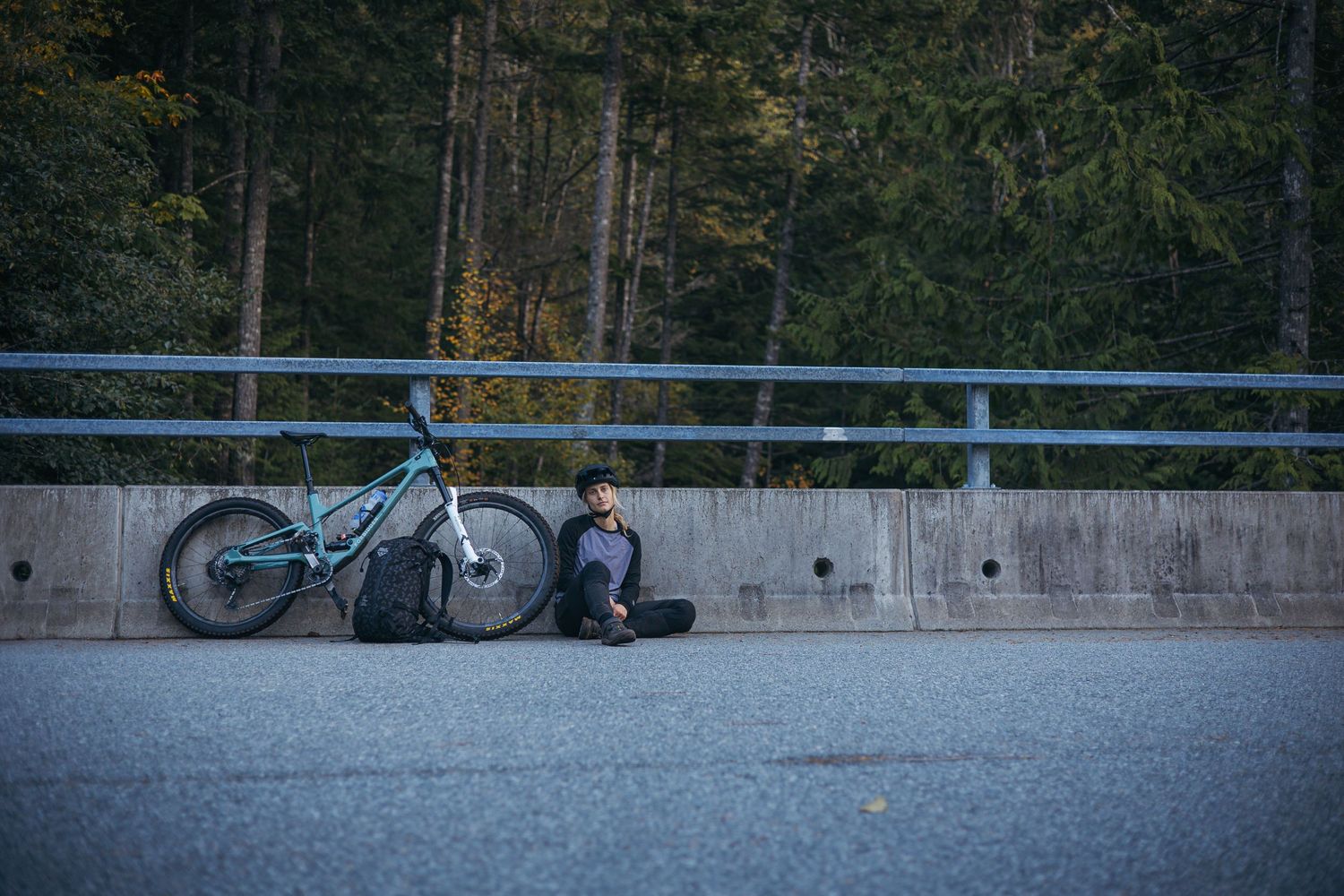 Mountain bike and gear resting against concrete barrier at scenic viewpoint.