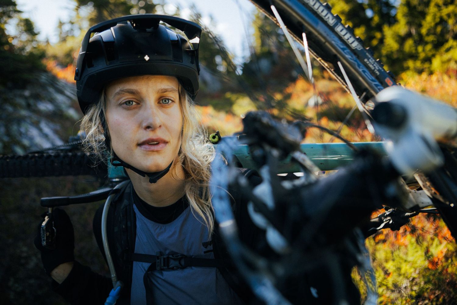 Mountain biker taking break on forested trail during autumn season.