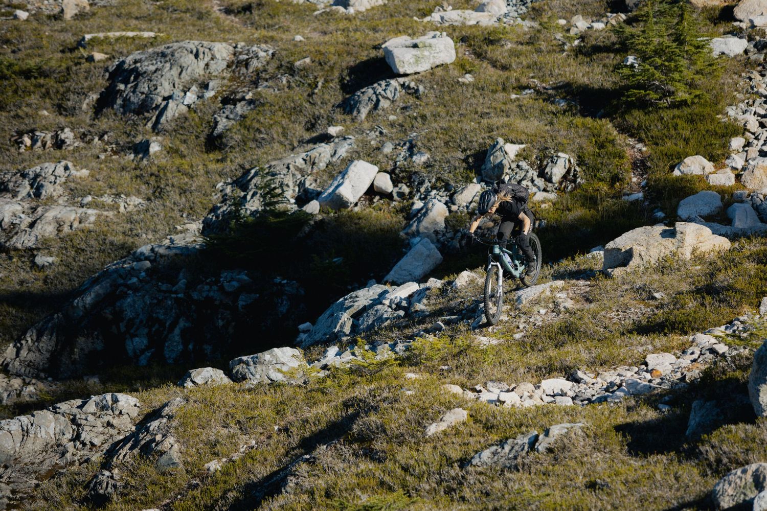 Mountain biker navigates technical rocky terrain in alpine environment.