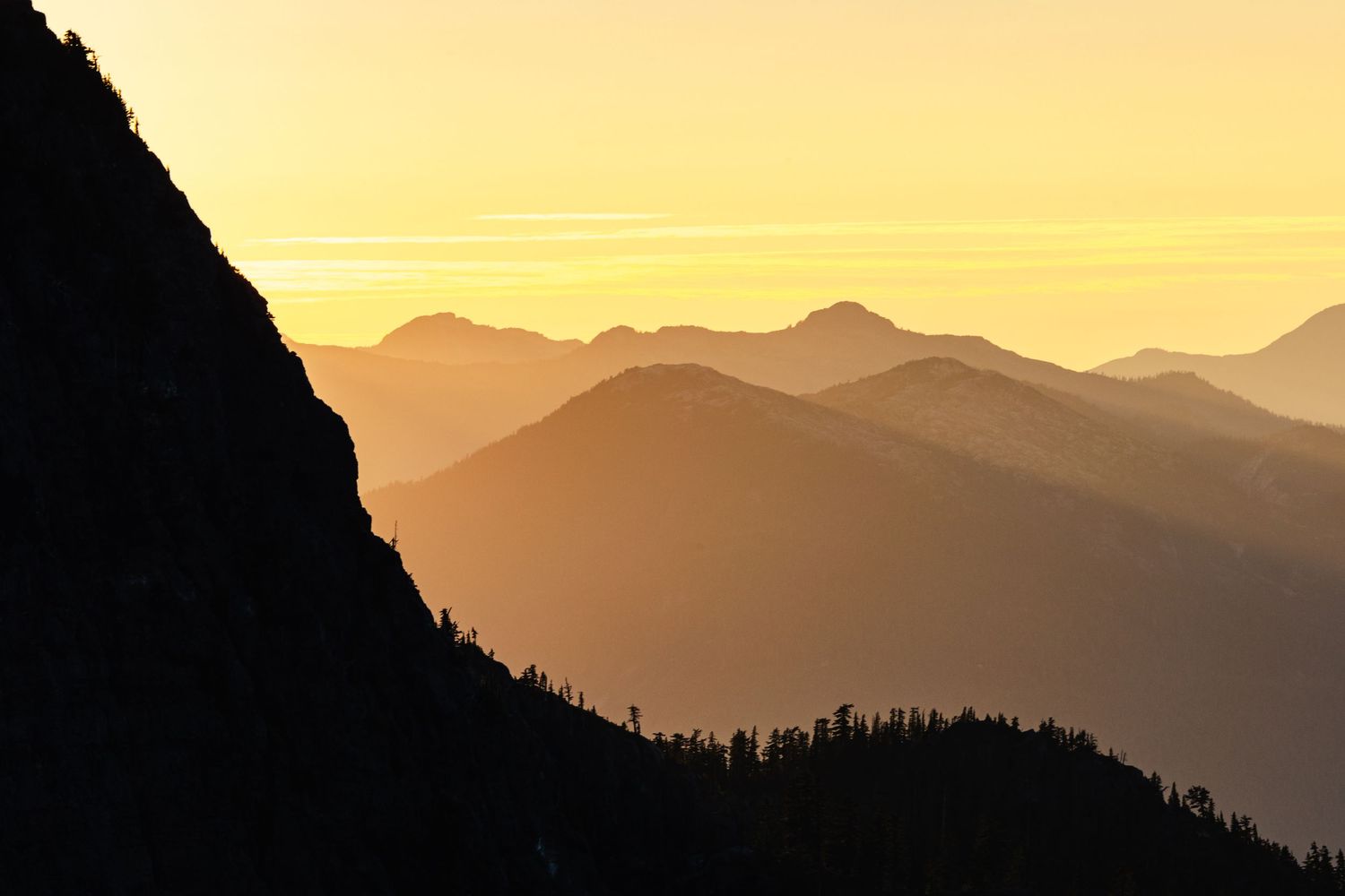 Layered mountain silhouettes at sunset create dramatic orange gradient effect.