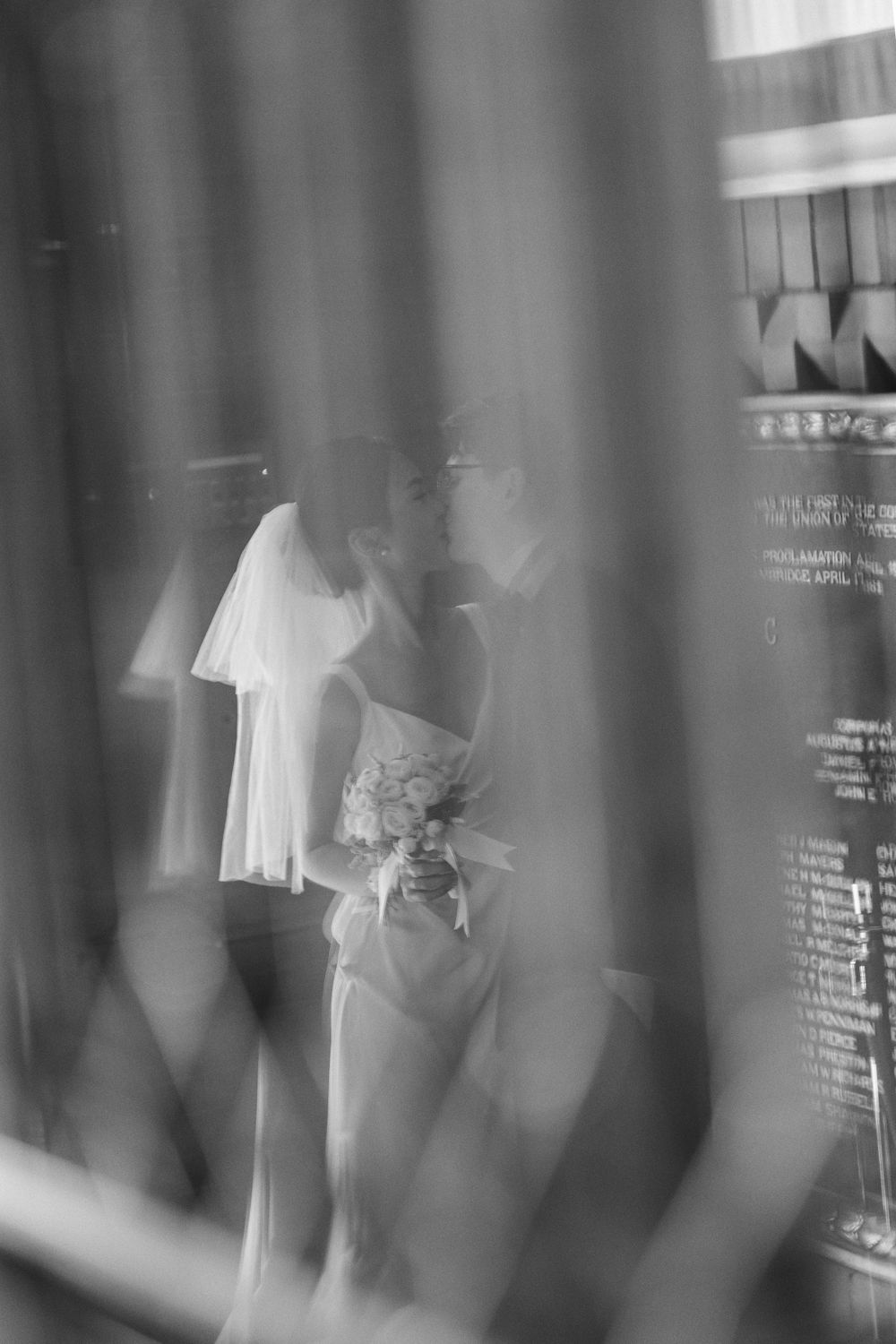Artistic black and white photo of wedding couple through textured glass.