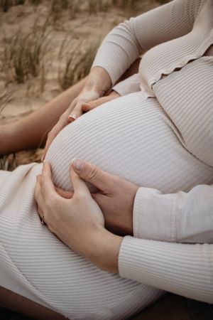 Close up of mum and dad holding pregnant belly.