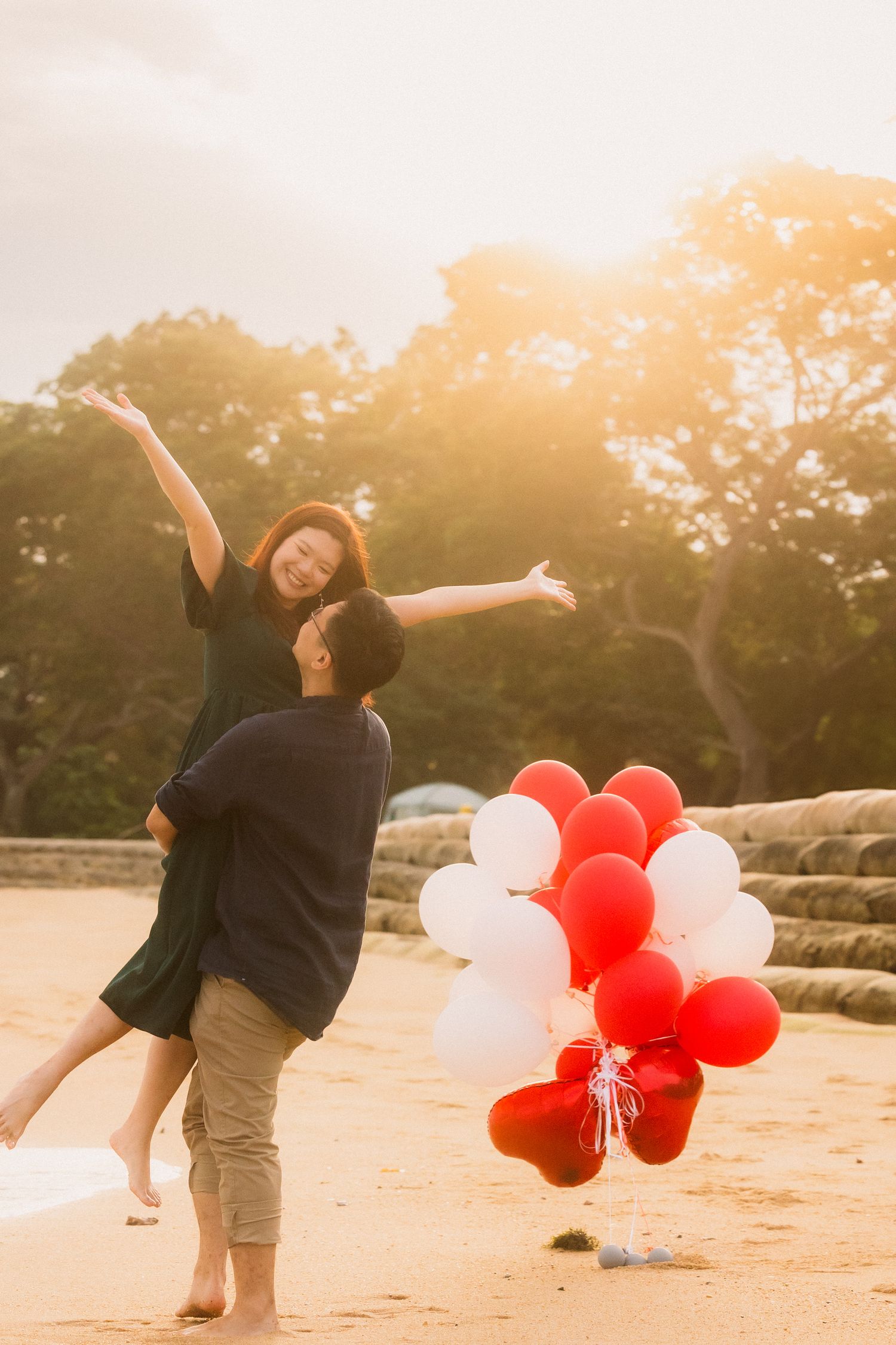 Person dancing joyfully on a beach at sunset with red and white balloons in a flowing sequence of movements.