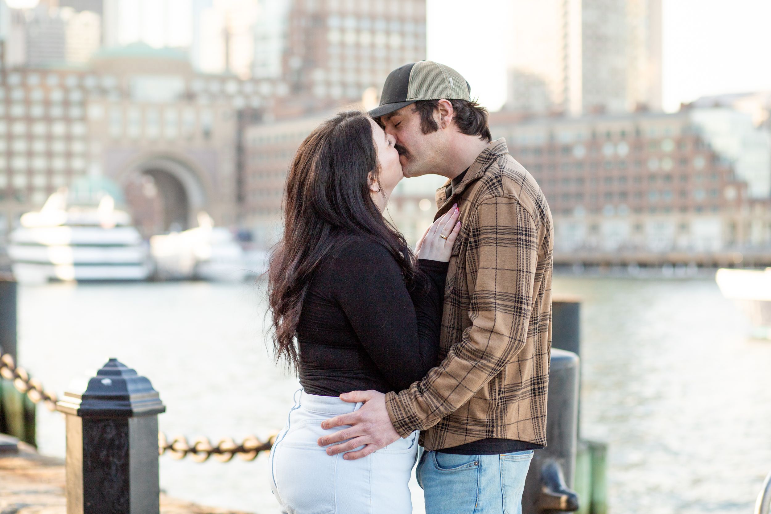 photoshoot in boston seaport; couple along fan pier park with boston in the background