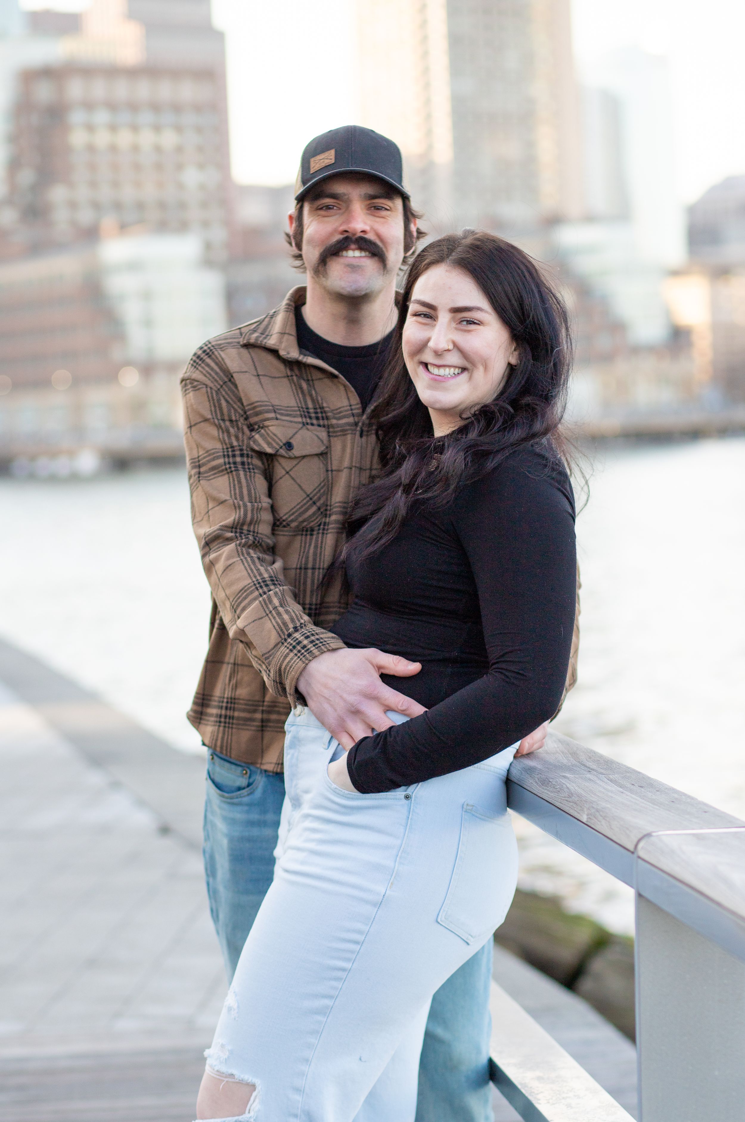 photoshoot in boston seaport; couple walks along fan pier park with boston in the background