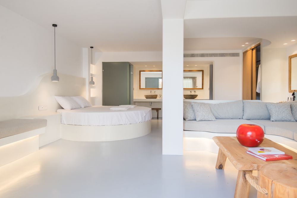 Bright open plan living space with white decor, circular bed and modern furniture.