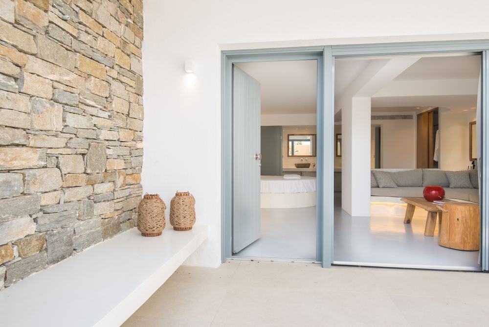 Modern entrance with stone accent wall and light blue sliding doors leading to interior spaces.