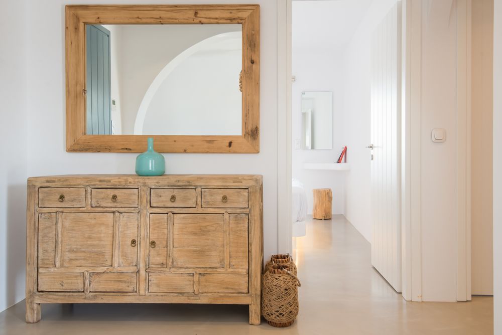 Rustic wooden console table with mirror and decorative accessories in modern hallway.