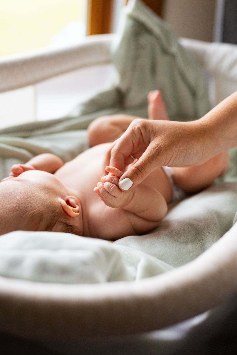 Gentle close-up photos of baby feet being tenderly held against white bedding.