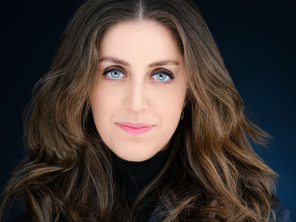 Professional headshot of woman with blue eyes and wavy brown hair.