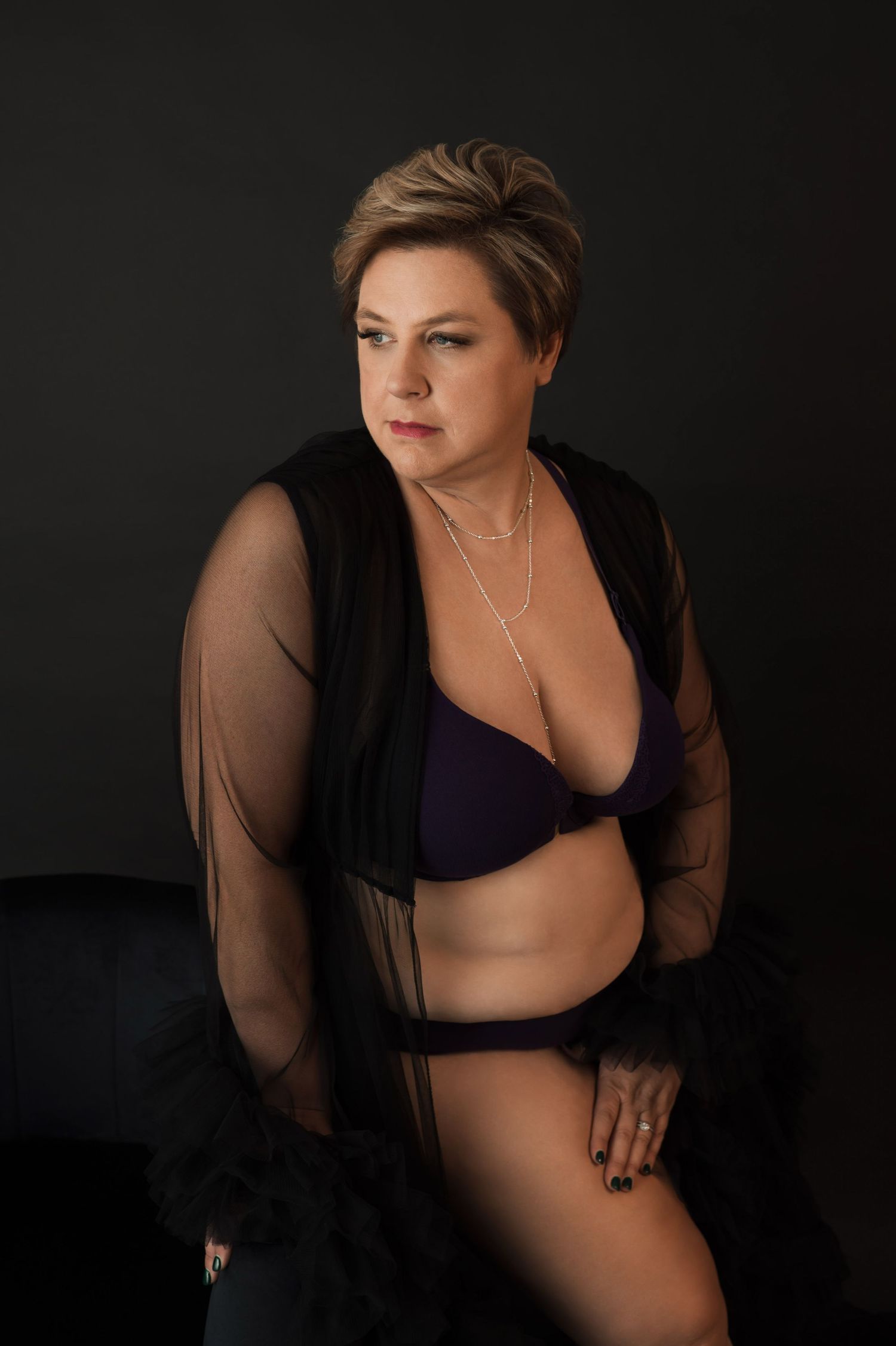 Moody boudoir photography with sheer details against dark background.