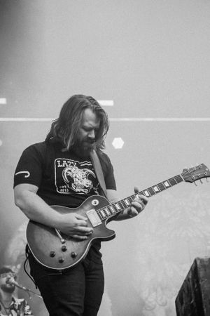 Guitarist plays Les Paul guitar while performing intensely in black and white.