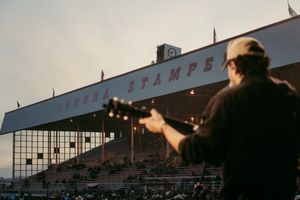 Silhouette by racetrack stands with historic Stamps grandstand visible in background at sunset.