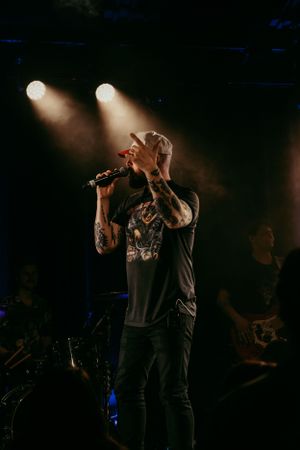 Concert performer singing emotionally into microphone on dark stage with dramatic lighting.