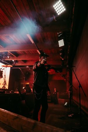 A performer on stage silhouetted against dramatic red lighting and fog effects during a concert performance.