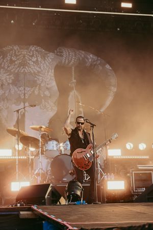 Rock musician performs on stage with dramatic backlighting and smoke effects.