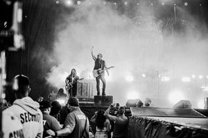 Black and white concert photo showing performers on stage with dramatic lighting and fog effects.