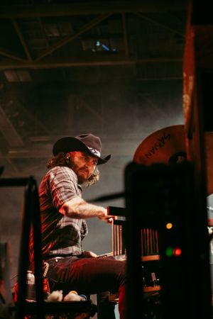 Musician plays piano in dramatic side-lit concert setting.