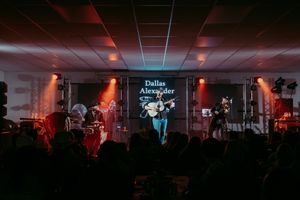 Band performs on dimly lit stage with red and blue lighting effects.