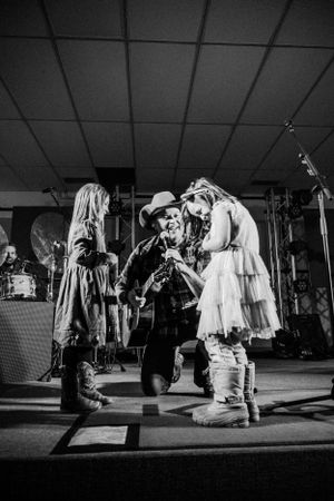 Three performers sing together on stage during a dynamic black and white concert moment.
