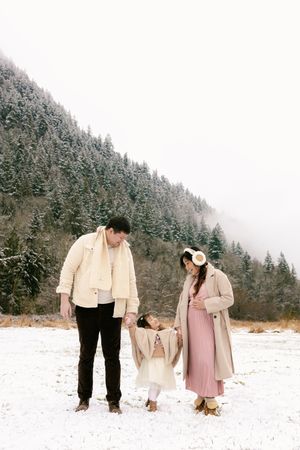Family photos in snowy winter landscape with pine trees.
