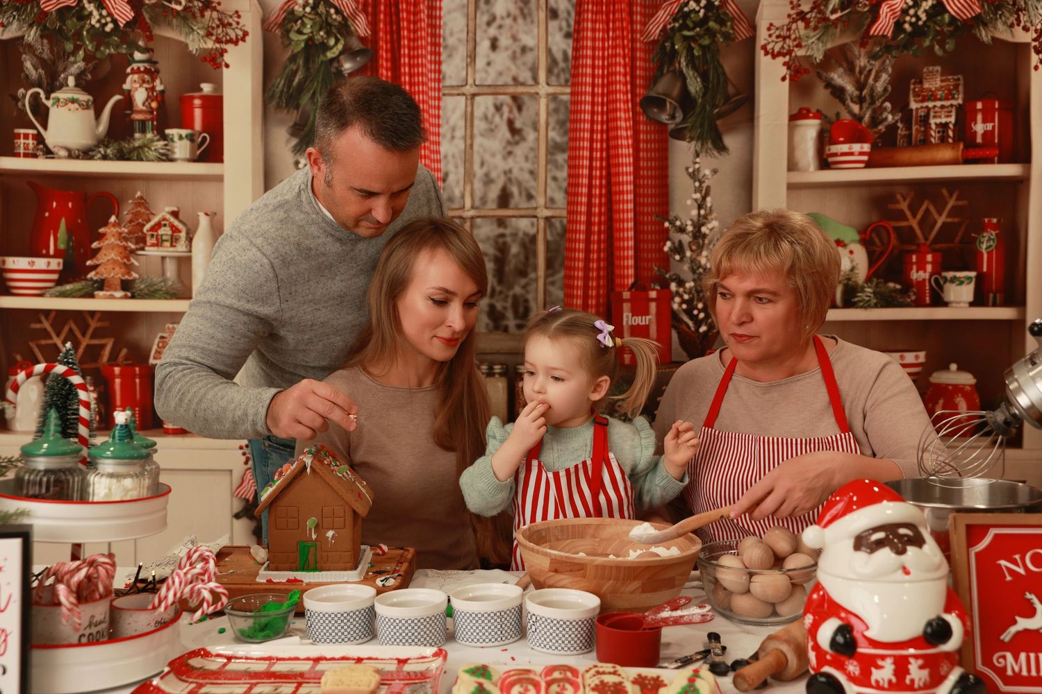 Family baking Christmas cookies together in a festive holiday kitchen decorated with Santa and seasonal ornaments.