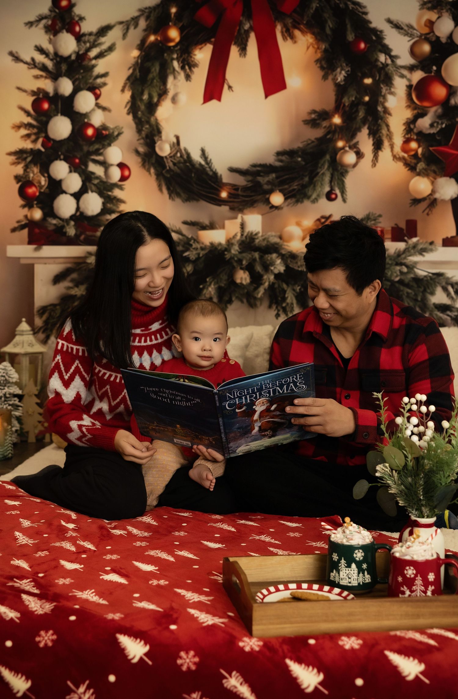 Family in red Christmas sweaters reading a holiday book together, surrounded by festive decorations and a Christmas tree.