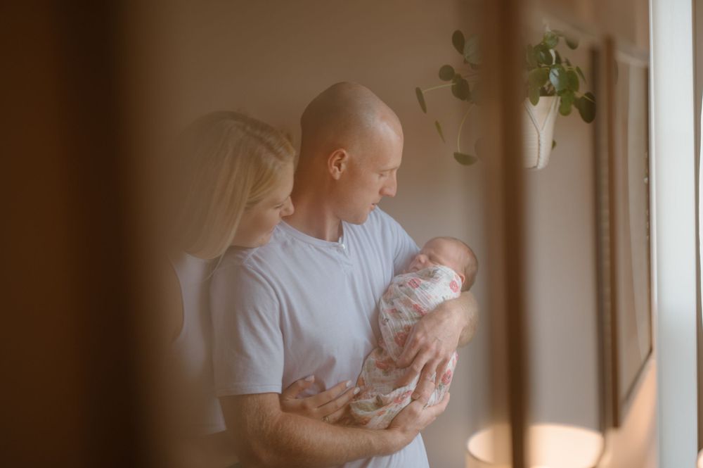 Tender moment with newborn baby in soft window light.