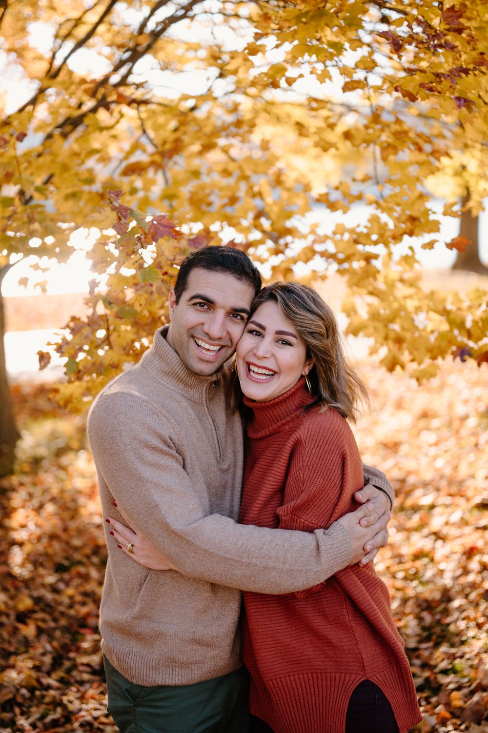 Couple sharing a joyful moment under vibrant autumn foliage.