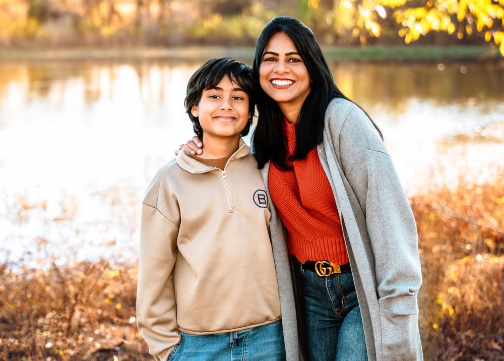A mother and child share a joyful moment together outdoors during golden hour sunset in autumn.
