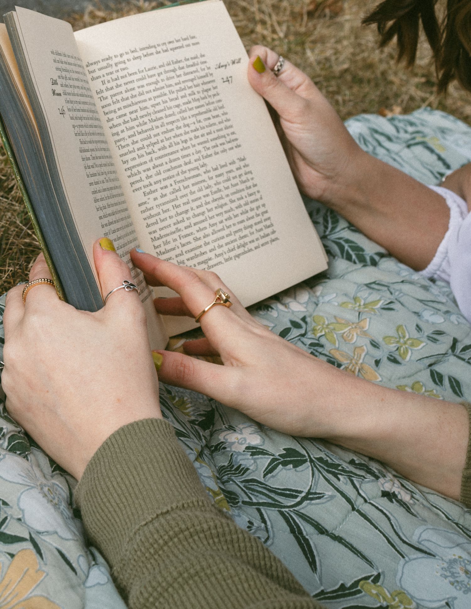 Close-up sequence of hands holding and reading a book on a floral print fabric. Luxury wedding photographer North Carolina