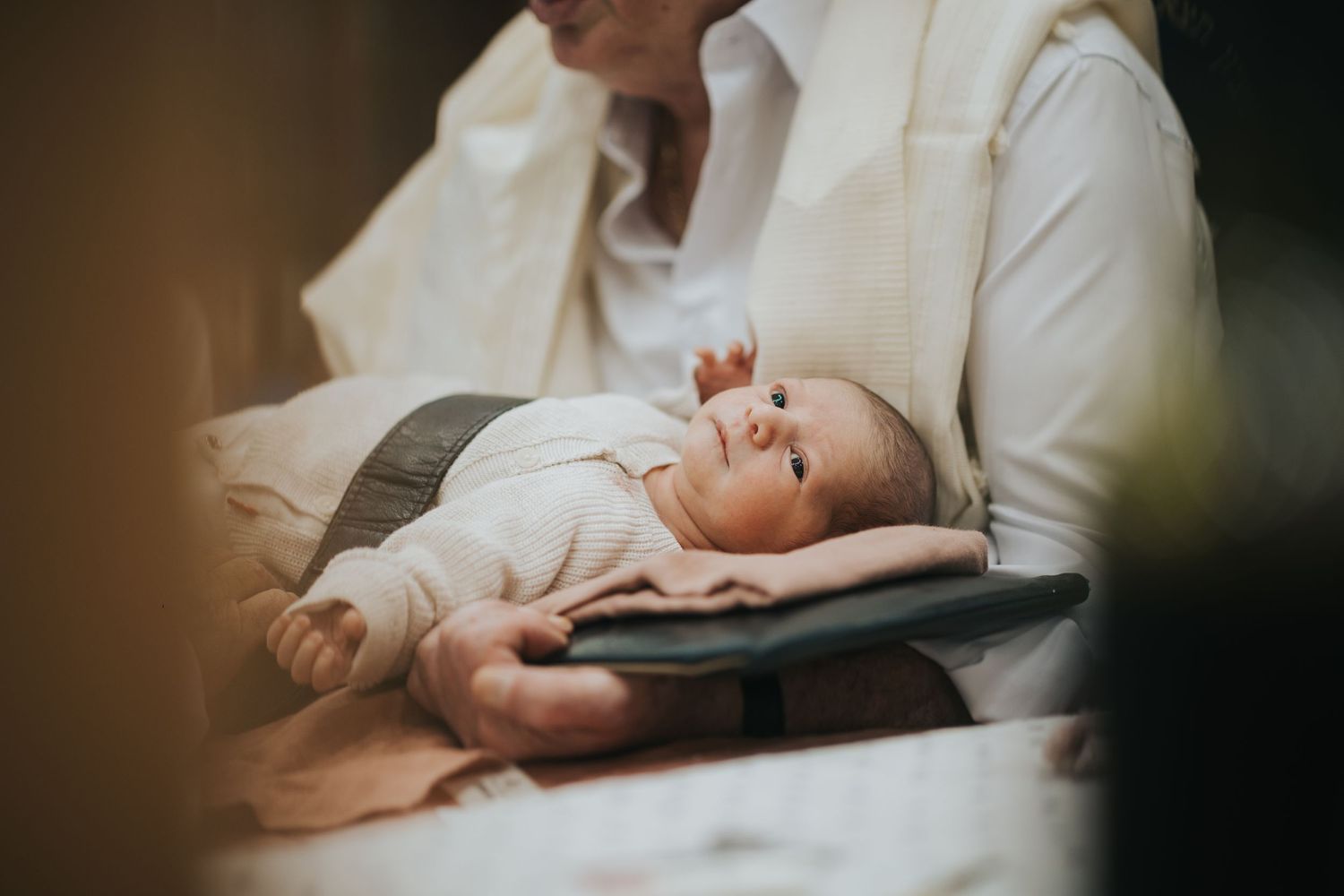 Baby in white clothing resting peacefully on soft fabric in natural light.