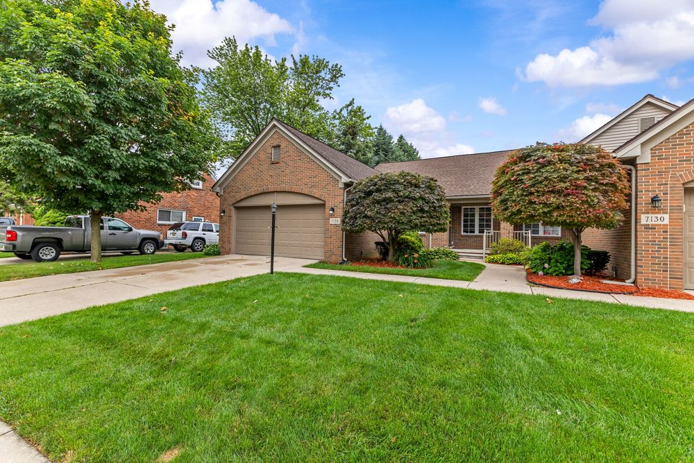 Brick home with attached garage, decorative Japanese maple trees, and lush green lawn.