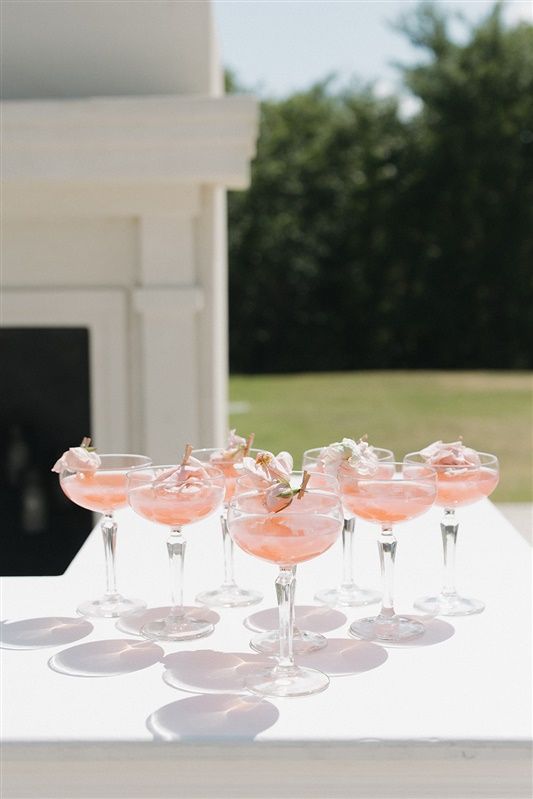 Elegant pink champagne cocktails in coupe glasses arranged on a white surface casting delicate shadows.