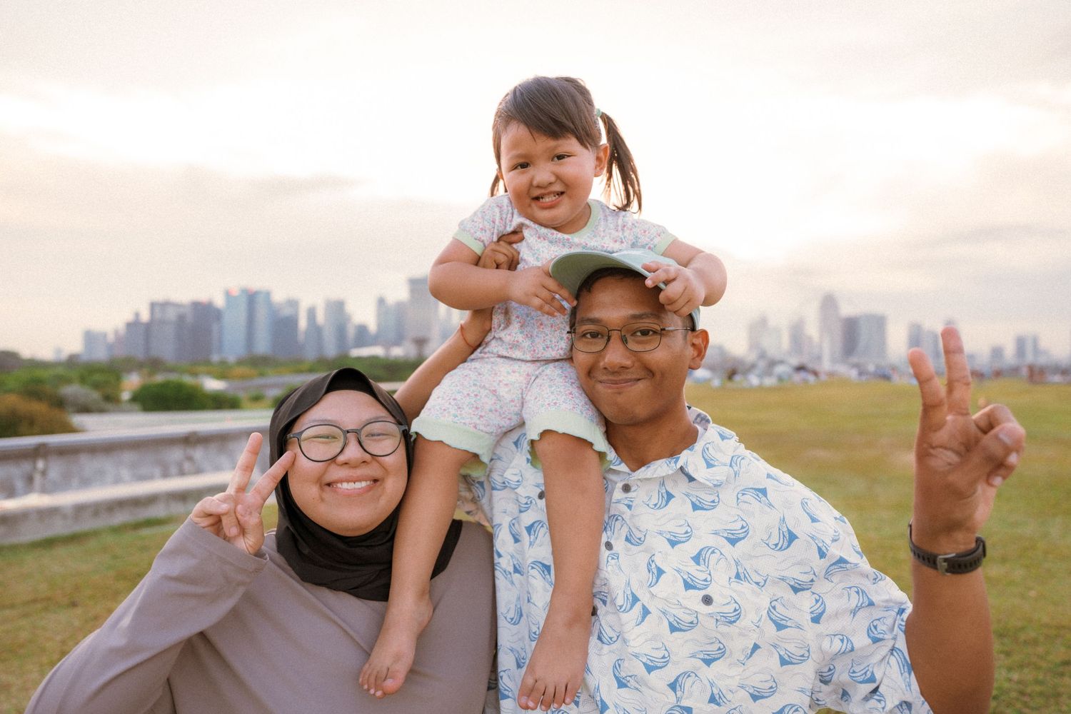 Happy family poses together against city skyline at sunset.